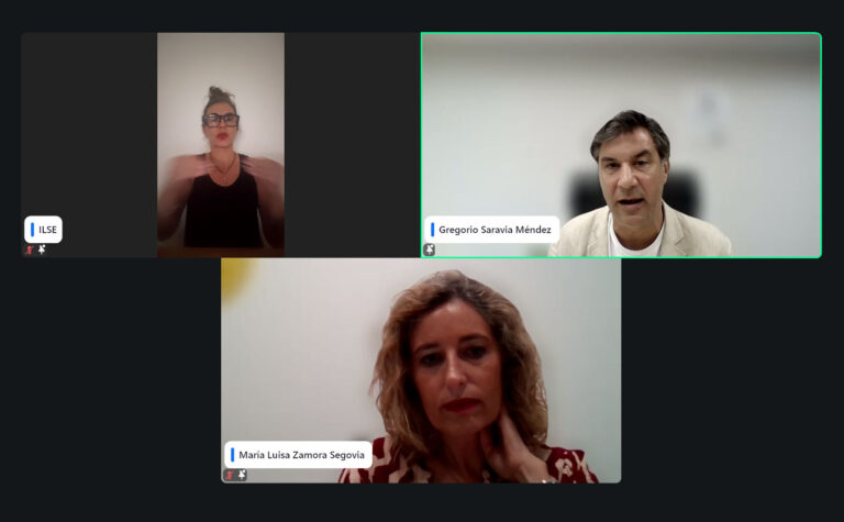 Una videollamada con tres participantes: una mujer que se comunica mediante lengua de signos en la esquina superior izquierda, un hombre que habla en la esquina superior derecha y una mujer que escucha en la parte inferior central. Las etiquetas con los nombres identifican a cada persona. Ley 8/2021